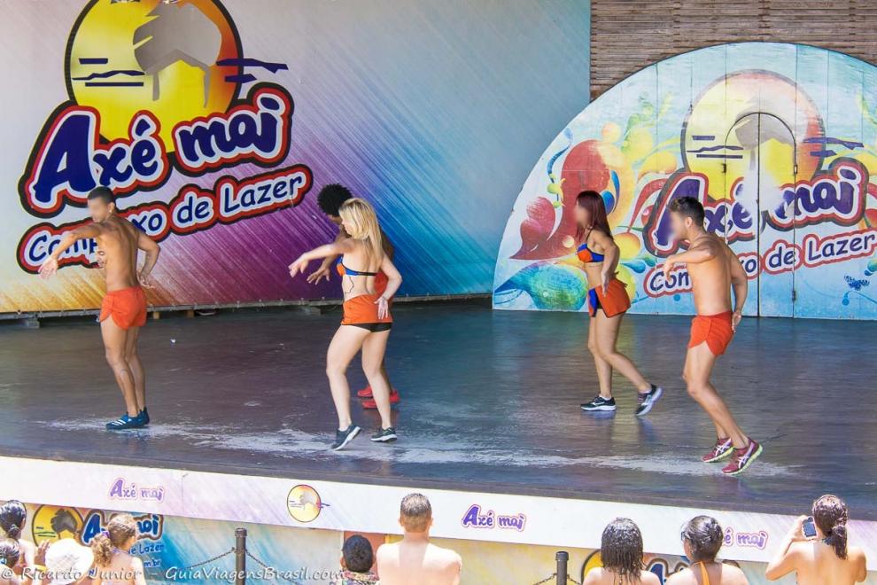 Imagem de cinco dançarinos ensinando passos aos turistas na Praia de Taperapuan.